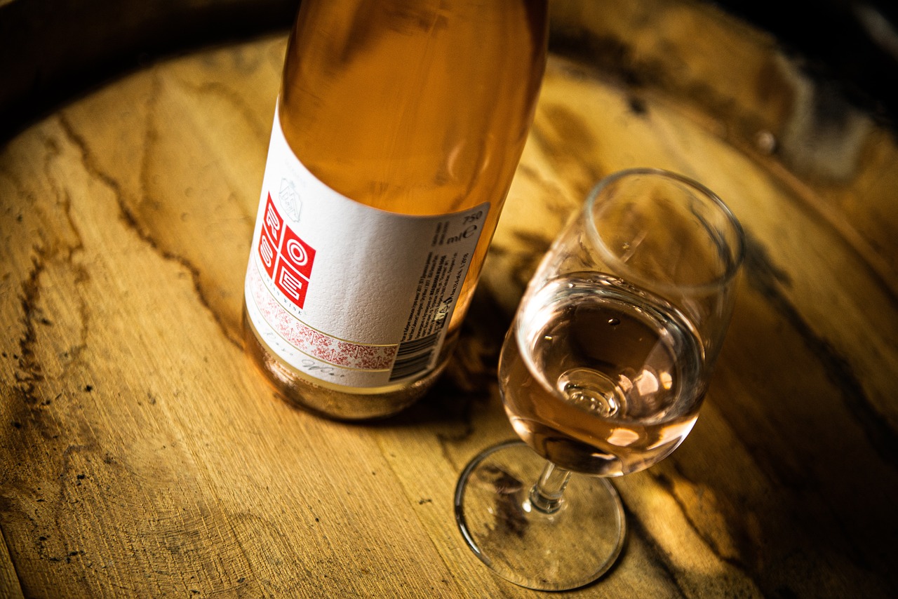 Flasche Roséweine neben einem Weinglas das mit Rotwein gefüllt ist.